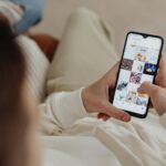 Kapalı alanda Instagram'da gezinmek için akıllı telefon kullanan, sosyal medya etkileşimi gösteren kişi. - Instagram takipçi satın al