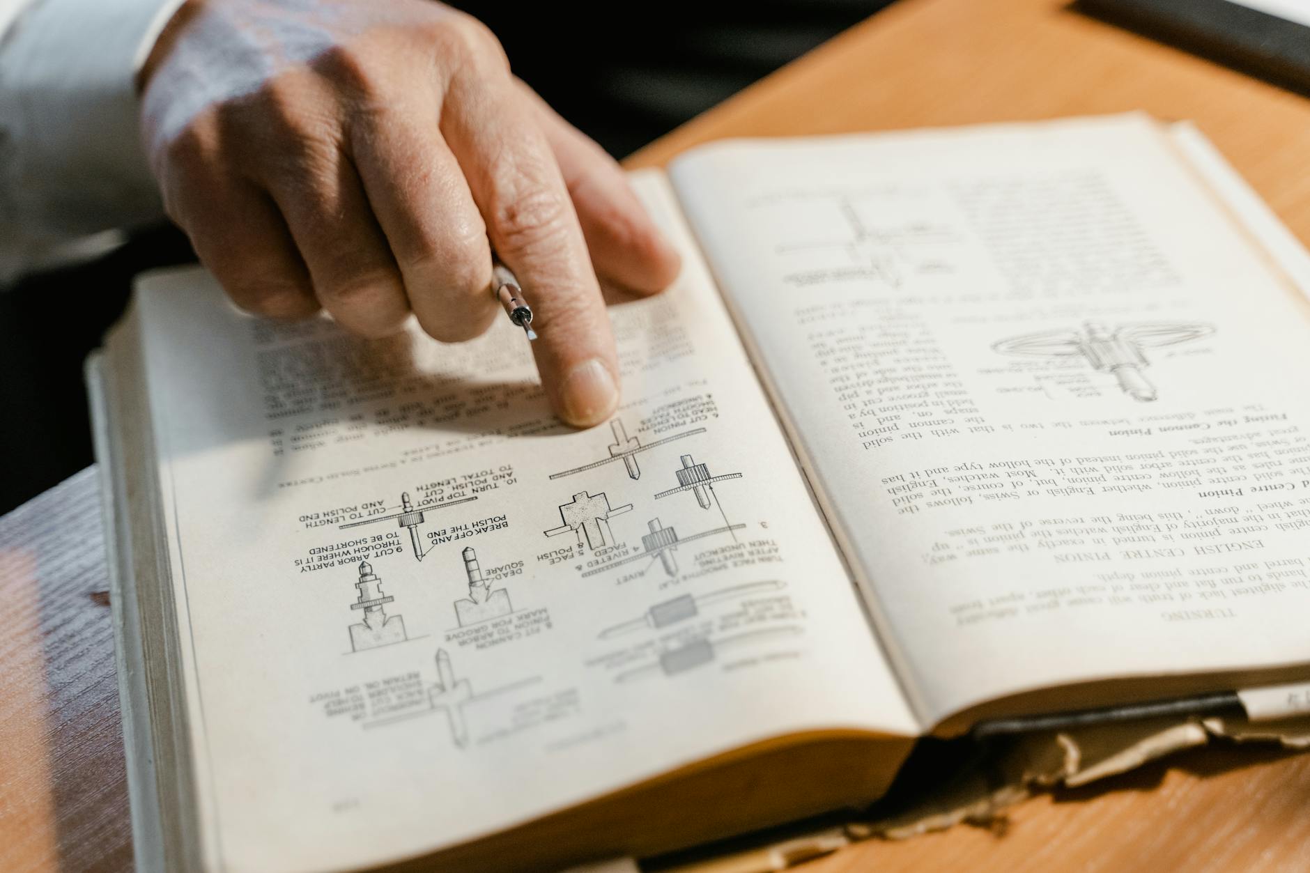 Açık bir kitaptaki bir diyagramı işaret eden bir el, mühendislik kavramlarına odaklanmış ve öğrenmeyi vurgulamaktadır. - SEO Çalışması